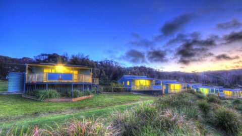 View on a row of Beachcomber Holiday Park houses with their light on inside during sunset.