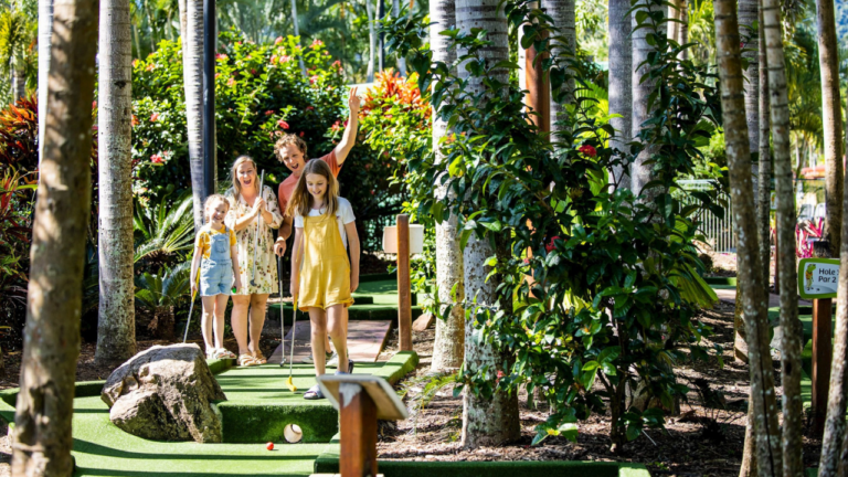 Family playing mini golf between palm trees at Big 4 Whitsunday Resort