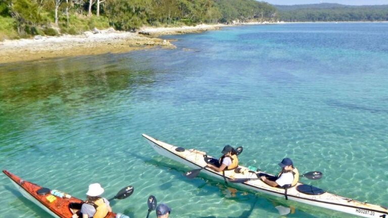 People on two kayaks in a bay with clear water.